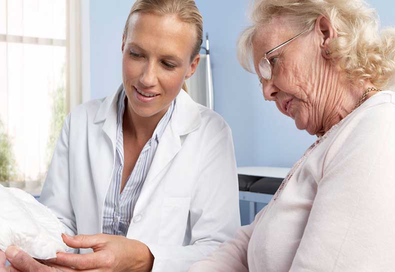 A doctor shows a lady a urinary incontinence product